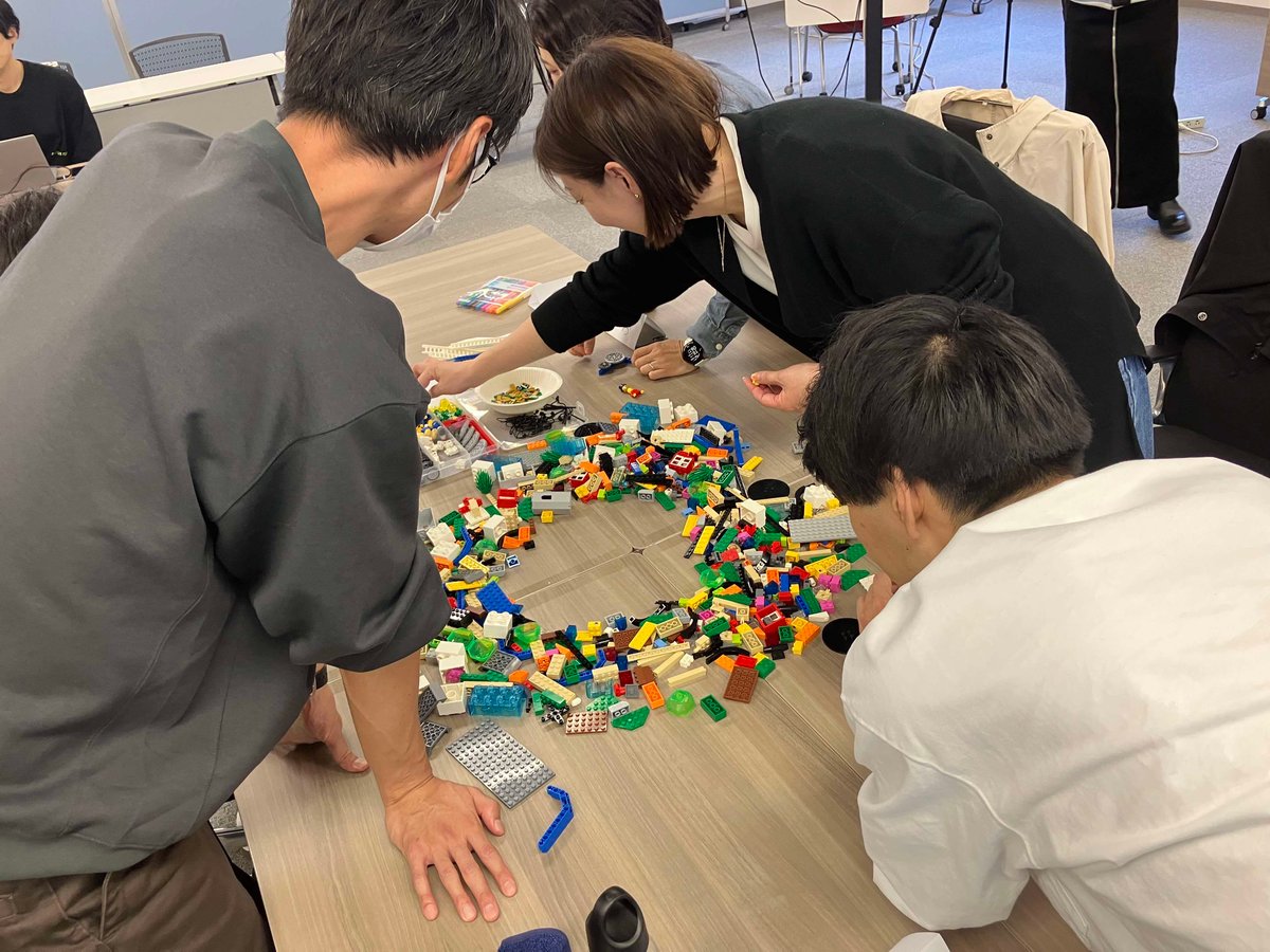 中小企業のチームメンバーが協働でレゴモデルを組み立てながら、課題解決に取り組む様子